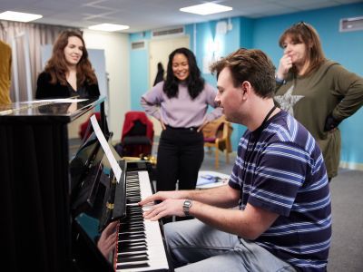 Music Therapy students in class around a piano
